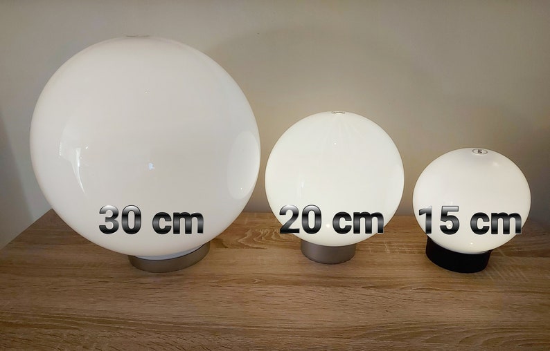 May include: Three white globe lamps of different sizes. The largest lamp is 30 inches in diameter, the middle lamp is 20 inches in diameter, and the smallest lamp is 15 inches in diameter.