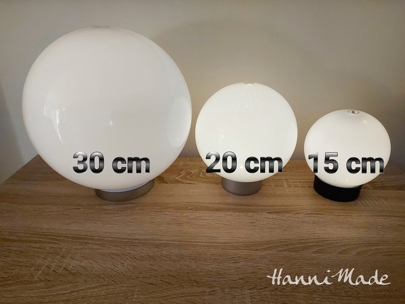 May include: Three white glass globe lamps of different sizes. The largest lamp is 30 cm in diameter, the middle lamp is 20 cm in diameter, and the smallest lamp is 15 cm in diameter.