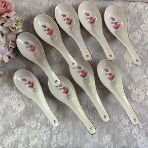 May include: Set of ten white porcelain soup spoons with a floral design. Each spoon features a pink rose with green leaves.