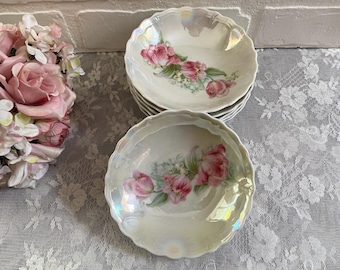 May include: Set of four white porcelain bowls with a floral design featuring pink and green flowers. The bowls have a scalloped edge and a pearlescent finish.