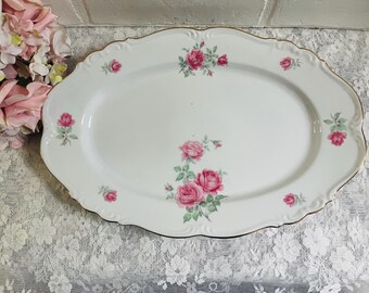 May include: Oval white porcelain serving platter with a scalloped edge and gold trim. The platter is decorated with pink rose floral patterns. A vintage-style serving dish for displaying food.