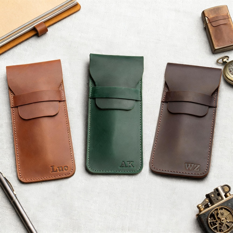 Pu&ograve; includere: Tre custodie per occhiali in pelle marrone, verde e marrone scuro. Ogni custodia ha una chiusura a patta e un dettaglio a cinturino. La custodia marrone &egrave; impressa con il nome "Luc", quella verde con "AK" e quella marrone scuro con "WZ".