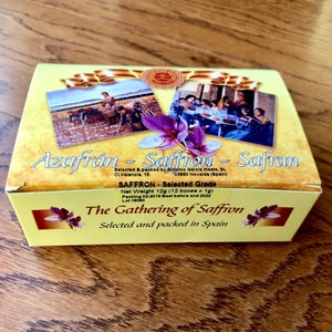May include: A yellow box with a picture of saffron flowers and a label that reads "Azafrán - Saffron - Safran". The box contains 12 grams of saffron, selected and packed in Spain. The label also includes the text "The Gathering of Saffron".