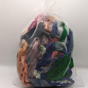 Puede incluir: Una bolsa de malla transparente llena de retazos de tela coloridos. Los retazos son de varios tonos de rosa, naranja, verde, azul y morado. La bolsa está atada en la parte superior y el contenido es visible a través de la malla.