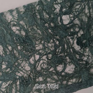May include: Close-up of a textured paper with a sea teal color. The paper has a fibrous, interwoven appearance, with the text "Sea teal" in a white, handwritten font at the bottom.