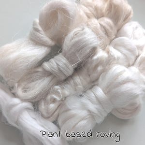 Op de afbeelding: Close-up van verschillende bundels plantaardige roving in tinten wit en crème. De tekst "Plant based roving" is in handschriftstijl onderaan de afbeelding geschreven. De roving ziet er zacht en pluizig uit, ideaal voor textielkunstprojecten.