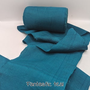 May include: A roll of teal fabric with a frayed edge, unrolled to reveal more of the same material. The text "Fantastic teal" is printed at the bottom. The fabric has a slightly textured appearance.