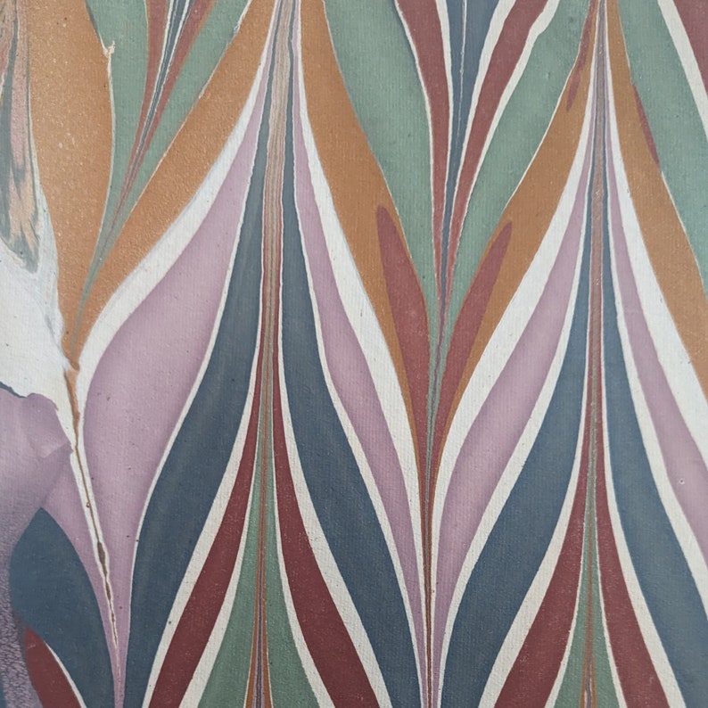May include: Abstract artwork with a pattern of curved, elongated shapes in shades of orange, green, blue, and red, separated by white lines. The design has a marbled effect, creating a flowing, organic appearance. The background is a light, off-white colour.