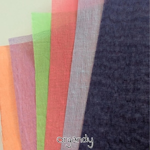 Könnte beinhalten: Eine Auswahl an transparenten Stoffmustern in den Farben Orange, Rosa, Grün, Koralle, Lavendel und Marineblau. Das Wort "organdy" ist in Schreibschrift unten rechts im Bild geschrieben.