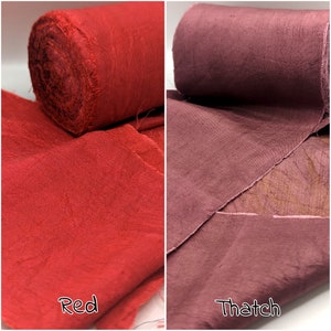 May include: Two fabric rolls, one bright red and the other a muted reddish-brown color. The red roll is labeled "Red" and the other "Thatch". The fabric appears to be a textured weave, possibly linen or cotton.
