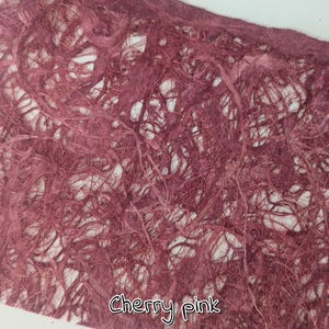 May include: Close-up of a sheet of cherry pink handmade paper. The paper has a textured, fibrous appearance with a network of interwoven strands. The text "Cherry pink" is written in a cursive font at the bottom.