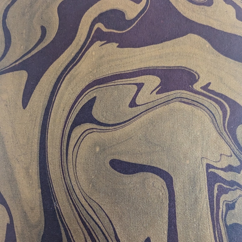 May include: Abstract artwork with a swirling pattern in shades of gold and deep purple. The design features fluid lines and a marbled effect, creating a sense of movement and depth. The colour palette is rich and sophisticated.