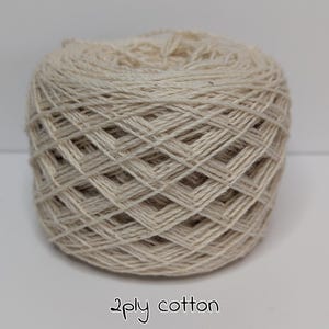 Peut inclure: Une pelote de fil de coton 2 brins de couleur naturelle. Le fil est de couleur beige clair, et le texte "2ply cotton" est &eacute;crit en cursive au bas de l'image. Ce fil convient &agrave; divers projets de cr&eacute;ation.