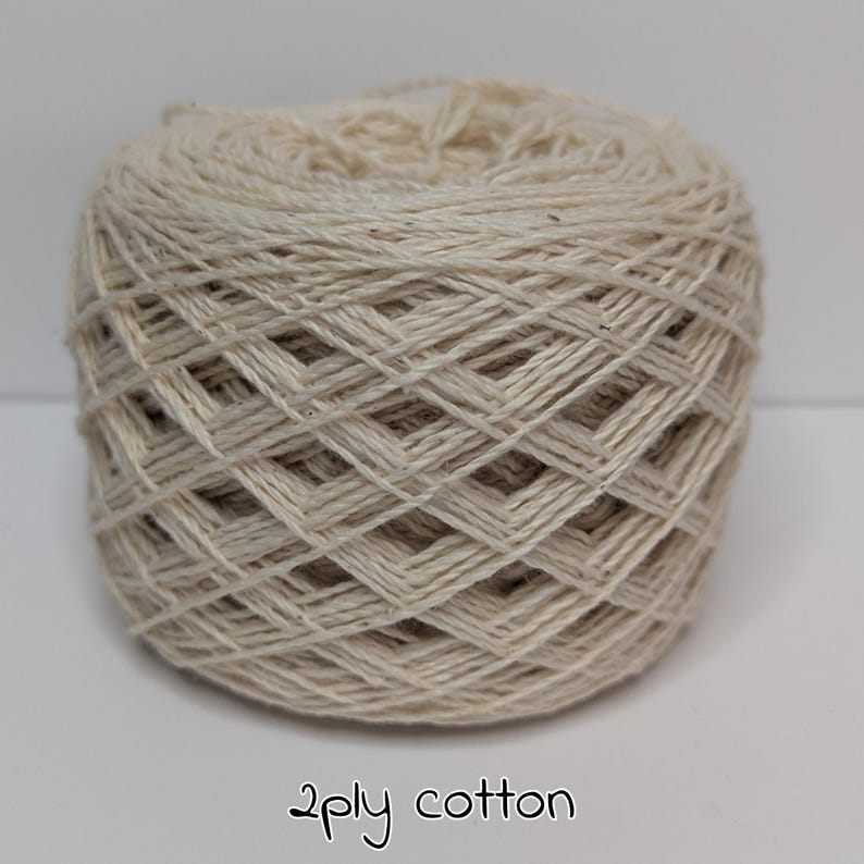 Peut inclure: Une pelote de fil de coton 2 brins de couleur naturelle. Le fil est de couleur beige clair, et le texte "2ply cotton" est &eacute;crit en cursive au bas de l'image. Ce fil convient &agrave; divers projets de cr&eacute;ation.