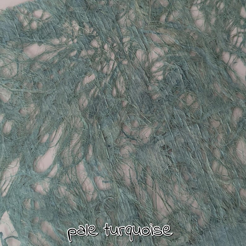 May include: Close-up of a pale turquoise textile with a textured, frayed appearance. The fabric has a woven look with visible strands and a soft, muted color. The words "pale turquoise" are written in a cursive font.