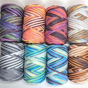 May include: Eight spools of colourful yarn are arranged in two rows. The yarn colours include purple, green, orange, pink, blue, and grey. The yarn is tightly wound, and the colours are arranged in stripes.