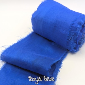 May include: A roll of royal blue fabric with frayed edges. The fabric is a vibrant shade of blue, with the words "Royal blue" written in a cursive font at the bottom. The fabric appears to be soft and lightweight.
