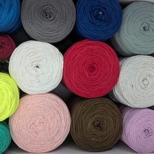 May include: A collection of colorful yarn skeins in various shades, including blue, gray, red, white, pink, and brown. The yarn is neatly arranged, showcasing the texture and color variations. Ideal for knitting and crochet projects.