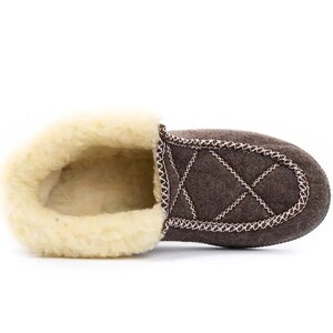 May include: Brown quilted slipper with a soft, white fleece lining. The slipper has a decorative stitch detail around the edge.