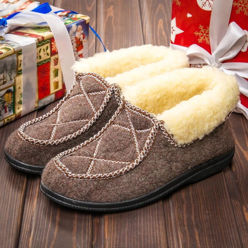 May include: A pair of brown quilted slippers with a white faux fur lining. The slippers have a black rubber sole.