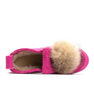 May include: Pink felt slipper with a fluffy brown pom-pom on top. The slipper has a soft, fuzzy lining.