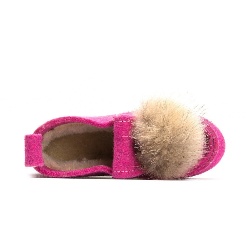 May include: Pink felt slipper with a fluffy brown pom-pom on top. The slipper has a soft, fuzzy lining.