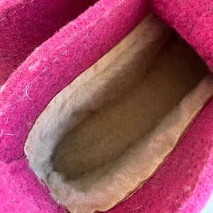 May include: Close-up of the inside of a pink felt slipper with a beige fleece lining.
