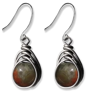 May include: A pair of silver-toned wire-wrapped earrings. Each earring features a teardrop-shaped design with a wire cage holding a round, speckled stone with shades of gray, brown, and red. The earrings have a simple hook closure.