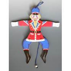 May include: A wooden toy soldier puppet with a red and blue uniform, a black belt, and a white face. The puppet has a string attached to its legs, allowing it to be pulled up and down.