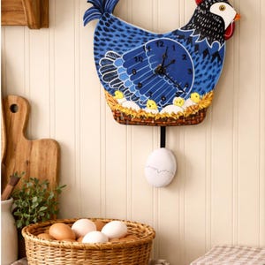 May include: A whimsical blue chicken-shaped wall clock with a pendulum egg. The clock face is a blue circle with black hands and white numbers. The clock has a red comb and a basket with yellow chicks. A basket of eggs sits below.