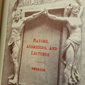 May include: A vintage book cover with a black and white image of two figures holding up a banner that reads "Henry Altemus Company". The text "Nature, Addresses, and Lectures" is printed in red below the banner. The author's name, "Emerson", is printed in red below the text.