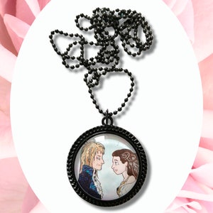 May include: A black chain necklace with a round glass pendant featuring a black and white illustration of a man and woman looking at each other.