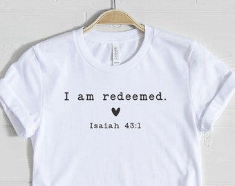 May include: White t-shirt with the text "I am redeemed." and a small heart symbol. Below the text is "Isaiah 43:1".