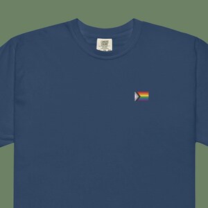 Puede incluir: Una camiseta azul marino con una pequeña bandera del orgullo arcoíris bordada en el pecho izquierdo.