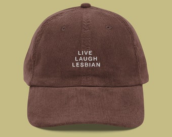 May include: A brown corduroy baseball cap with white embroidered text that reads "LIVE LAUGH LESBIAN".