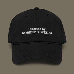 May include: Black baseball cap featuring the white embroidered text "Directed by ROBERT B. WEIDE". The cap has a curved peak and a classic six-panel design. A stylish accessory for everyday wear.