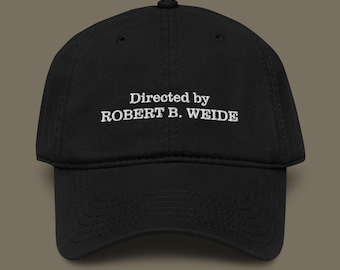 May include: Black baseball cap with the text "Directed by ROBERT B. WEIDE" embroidered in white. The cap has a curved brim and a classic six-panel design. A stylish accessory for everyday wear.