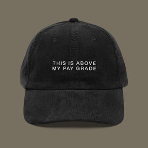 May include: Black corduroy baseball cap with white embroidered text that reads "This is above my pay grade".