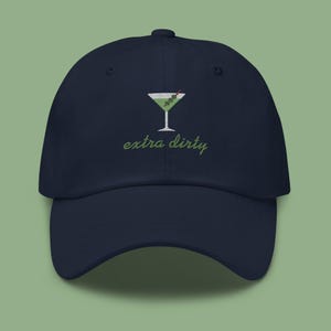 May include: A navy blue baseball cap with an embroidered green martini glass and the text "extra dirty".