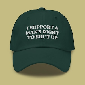 May include: A dark green baseball cap with white embroidered text that reads "I support a man's right to shut up".