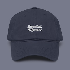 May include: Navy blue baseball cap with the embroidered text "Bisexual Menace" in white script. The cap has a curved brim and a classic six-panel design. A casual accessory for everyday wear.