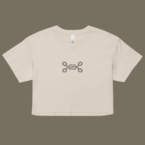 May include: A beige cropped t-shirt with a simple black graphic of two crossed scissors.