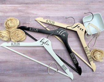May include: Four wooden hangers with black lettering. The hangers are labeled "Bride", "Bridesmaid", "Maid of Honor", and "Kylie". The hangers also have the date "8.23.20" printed on them.