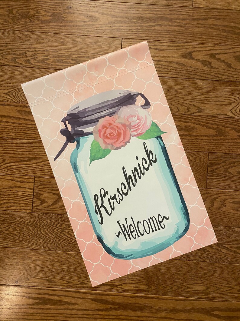 May include: A blue mason jar with a pink and white floral design and the text "Kirschnick -Welcome-" on a pink and white patterned background.