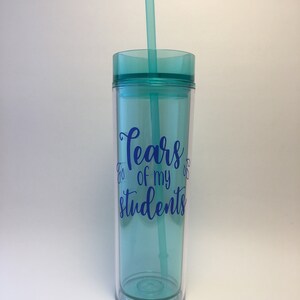 May include: A turquoise tumbler with a clear lid and a straw. The tumbler has the text "Tears of my students" printed on it in blue.