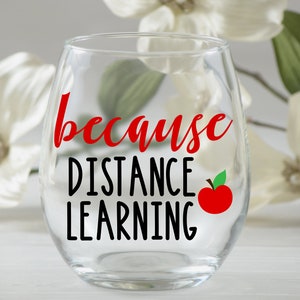 May include: A clear glass wine glass with the text "because distance learning" in black lettering and a red apple graphic.