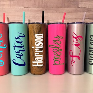 May include: Six personalized stainless steel tumblers with various colors and names. The tumblers are lined up in a row on a wooden surface. The names on the tumblers are Jennae, Carter, Harrison, Presley, Liz, and Skyler.