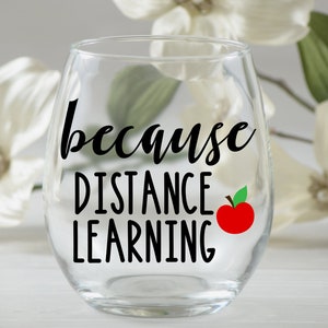 May include: A clear glass wine glass with the text "because distance learning" and a red apple with a green leaf on the side.