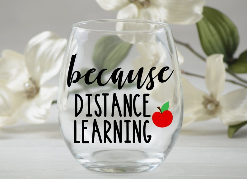 May include: A clear glass wine glass with the text "because distance learning" and a red apple with a green leaf on the side.