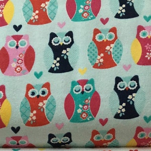 May include: A turquoise fabric with a repeating pattern of colorful owls. The owls have different colored bodies, wings, and eyes. There are small white hearts scattered throughout the fabric.